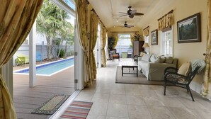 Amplia sala de estar con vista a la piscina, ventiladores de techo y un cómodo conjunto de asientos.