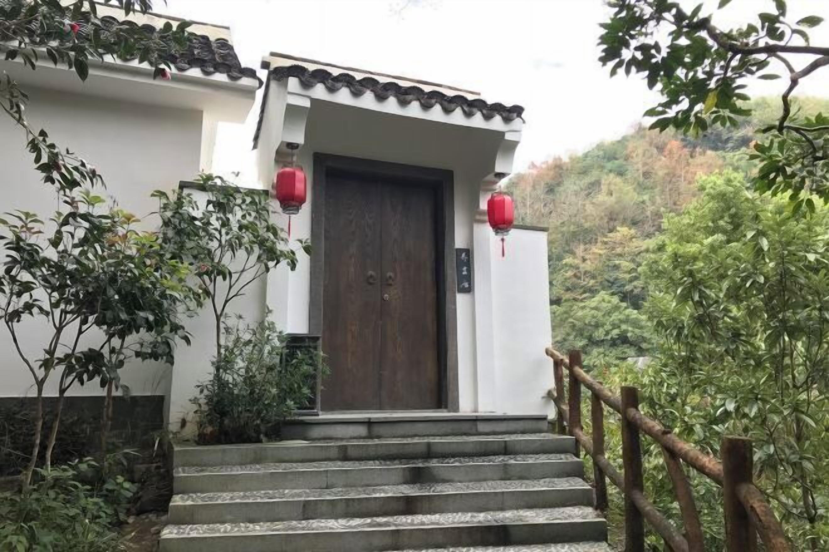 A traditional building with a wooden door, steps leading up to it, and red lanterns.