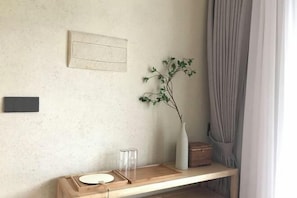 Una habitación minimalista con un aparador de madera, un florero con planta y un cuadro en la pared.