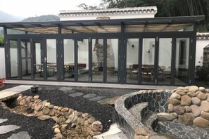 A modern glass-enclosed structure with a stone pathway leading to a seating area. - Yunjishan Hotspring Holiday Village (Xinfeng)