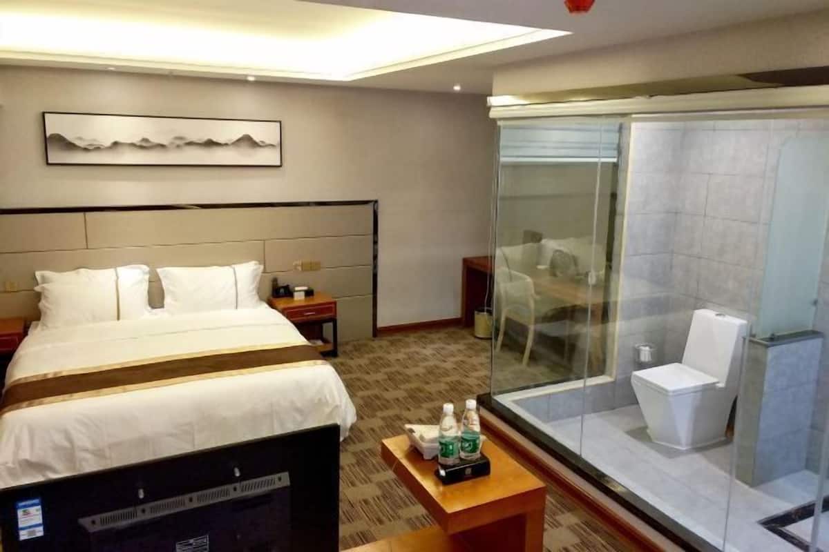 Une chambre d’hôtel comprenant un lit, une table de chevet et une douche séparée par des parois en verre.