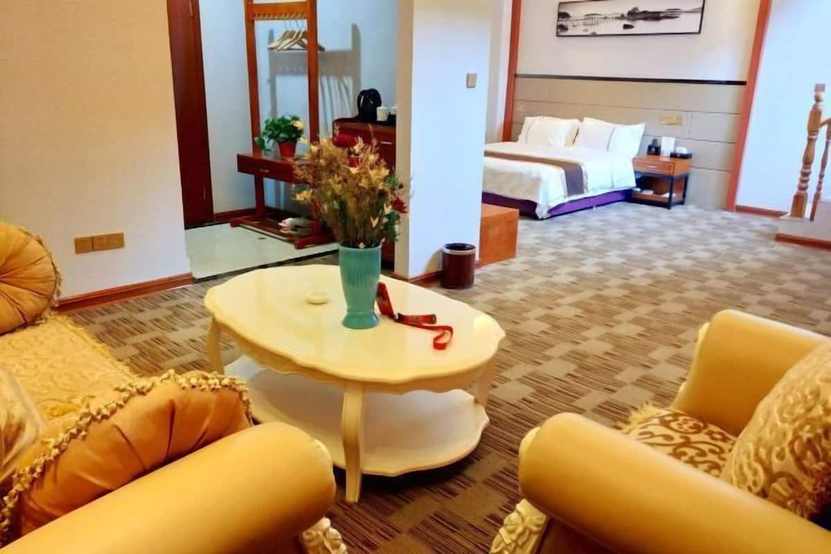 Une chambre d’hôtel avec un lit, une petite table sur laquelle se trouve un vase, une chaise et un canapé.
