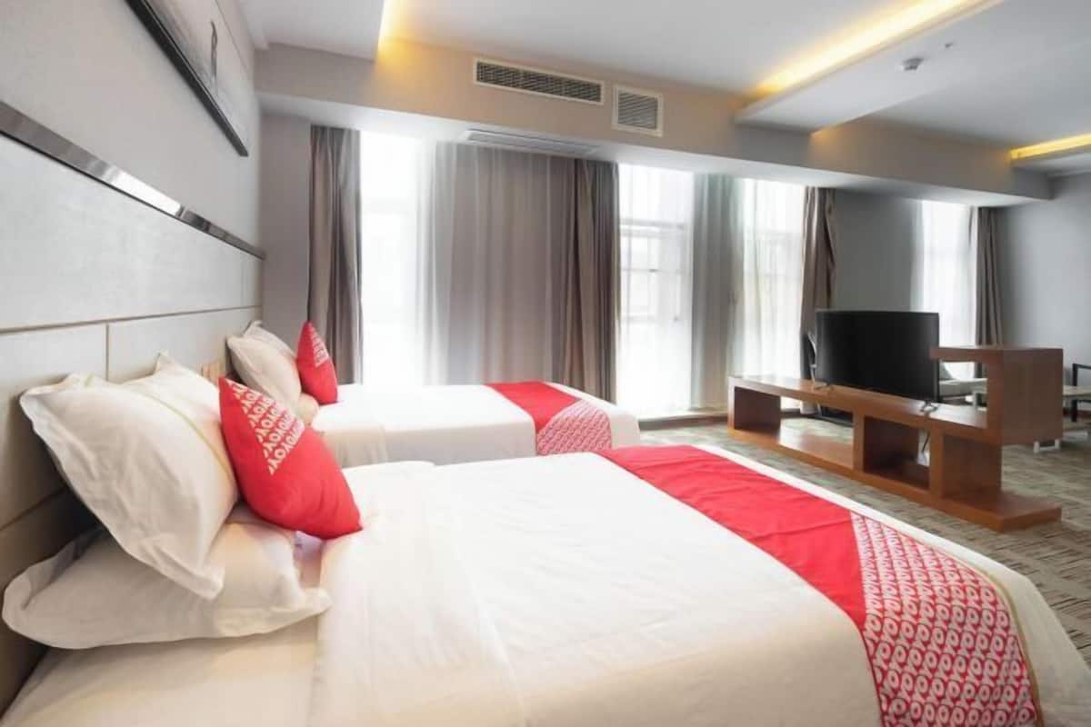Une chambre d’hôtel avec deux lits, une télévision et une grande fenêtre avec des rideaux.
