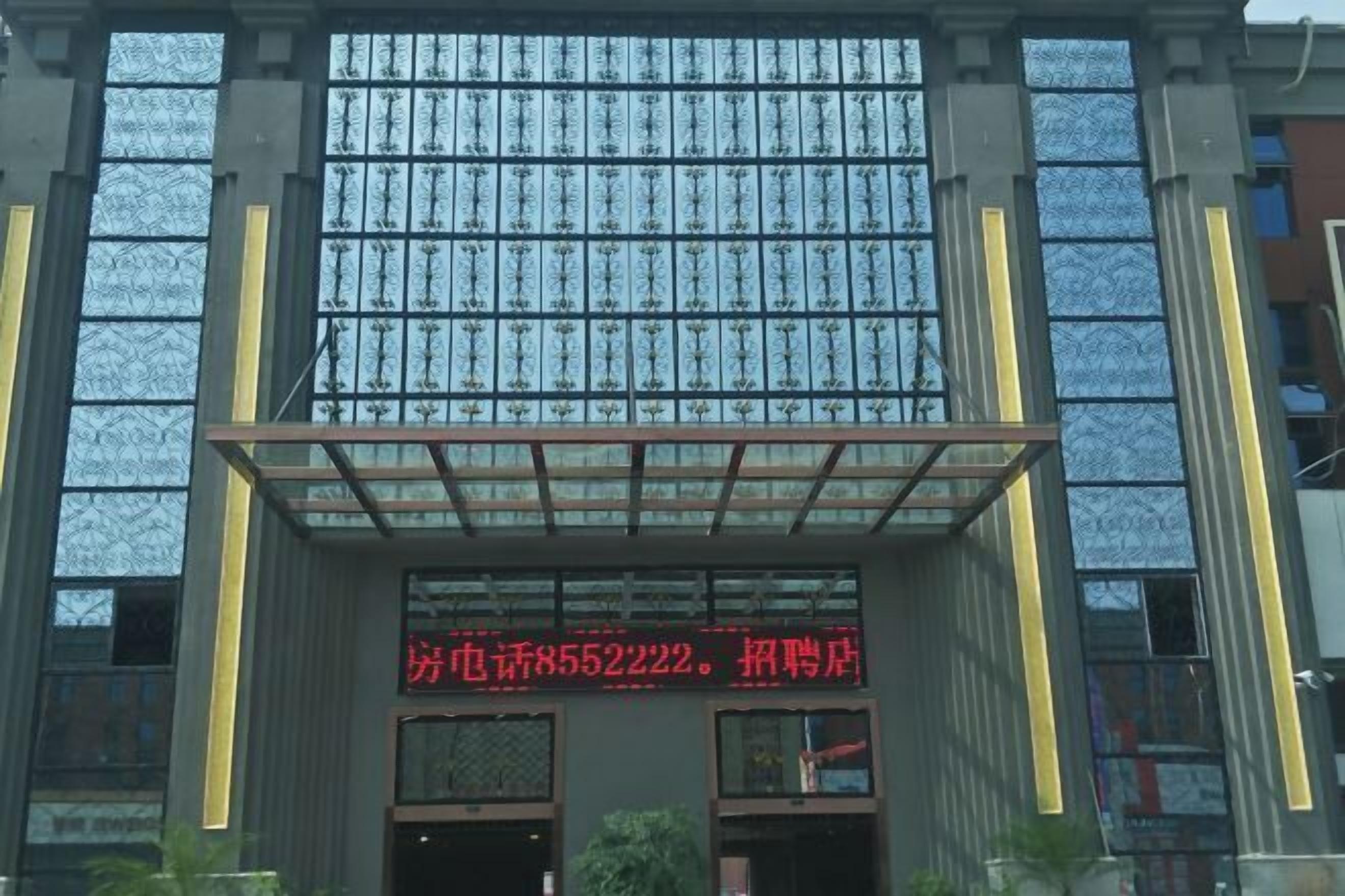 Une façade d’immeuble avec de grandes fenêtres et une enseigne rouge bien visible, avec du texte blanc.