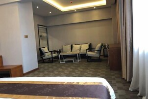 A hotel room with a bed, a seating area with two chairs and a table, and a large mirror on the wall.
