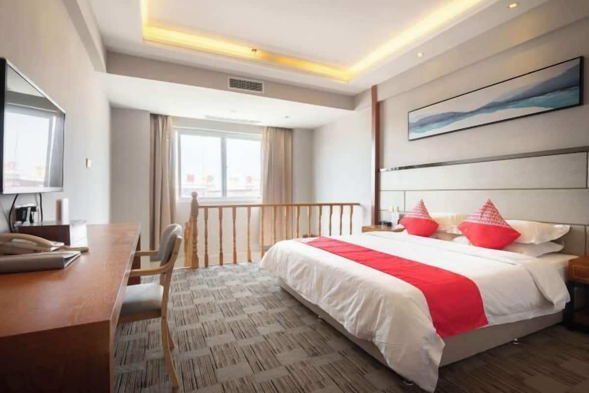 Une chambre d’hôtel avec un lit, un bureau, une chaise, une télévision et une fenêtre.