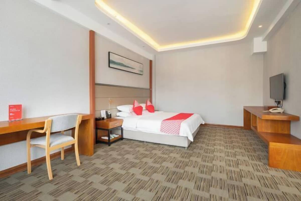 Une chambre d’hôtel équipée d’un lit, d’un bureau, d’une chaise et d’un téléviseur.