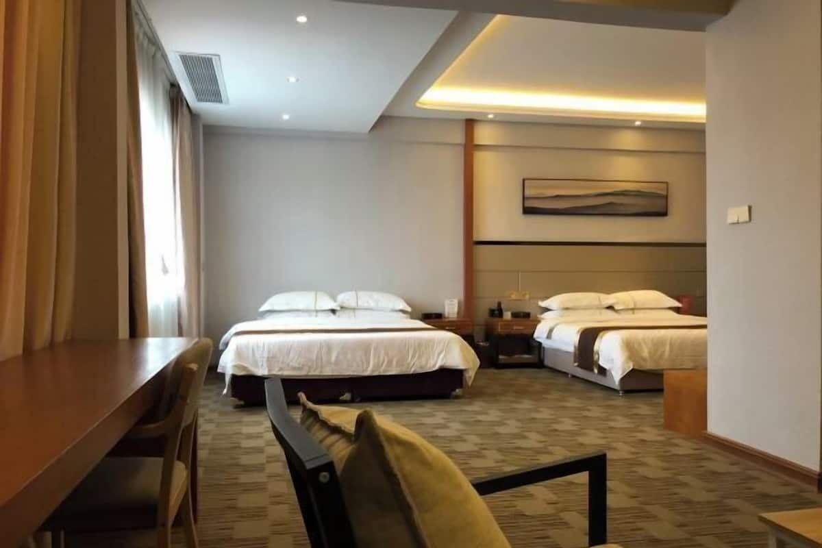 Une chambre d’hôtel avec deux lits, un bureau et une chaise.