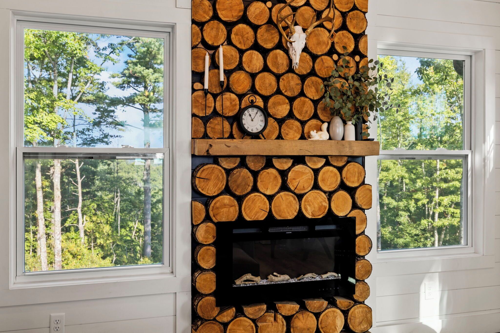 A fireplace with a log wall, a clock, and a plant.
