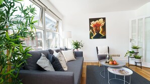 Een moderne woonkamer met een grijze bank, een salontafel en een plant in pot.