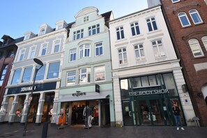 A street view with a row of buildings, including a store named 'Schuhka' and 'The Body Shop.'