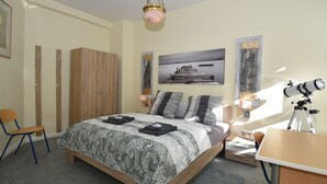Un dormitorio con cama, escritorio, silla, armario y un telescopio.