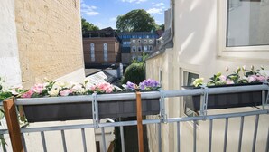 Un balcón con barandillas metálicas y jardineras con flores rosas y moradas.