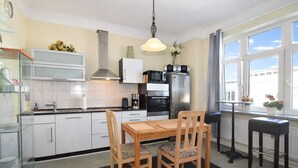 Una cocina moderna con armarios blancos, una mesa de comedor con sillas, una cafetera y un refrigerador.
