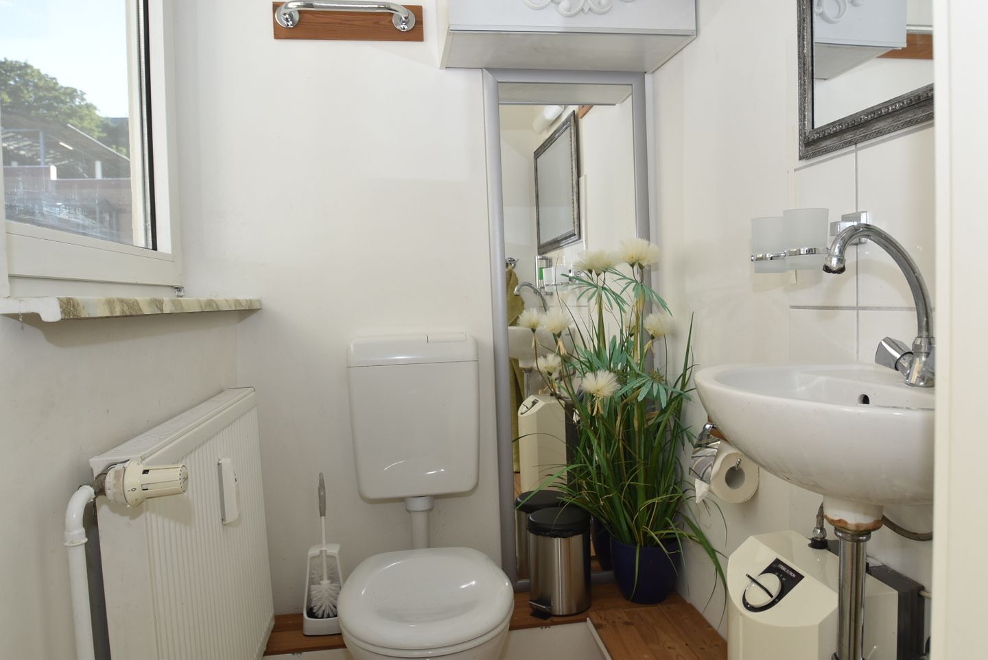 Een badkamer met toilet, bidet, wastafel en spiegel.