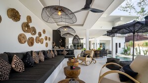 Een moderne woonkamer met een bank, salontafel en stoelen, een eethoek en een zwembad.