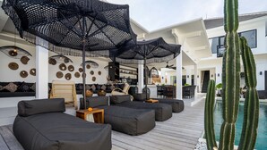 Een moderne buitenlounge met zwarte zittingen, een zwembad en decoratieve cactussen.