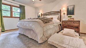 Ein Schlafzimmer mit einem Bett, einem Schminktisch, einem Deckenventilator, einem Fenster mit Vorhängen und einer Wandlampe.