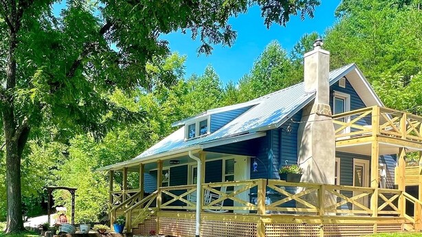 A wooden cabin with a porch, surrounded by lush greenery. - Riverside Relaxer Cottage w/Hot Tub+LRG deck+fireplace, w/ Little TN River View (Franklin)
