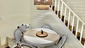 A dining area with a round table, two chairs, a woven hanging light fixture, and a staircase with white railings. - Riverside Relaxer Cottage w/Hot Tub+LRG deck+fireplace, w/ Little TN River View (Franklin)