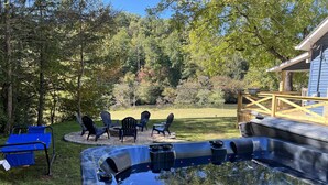 A hot tub surrounded by outdoor seating and a wooden deck. - Riverside Relaxer Cottage w/Hot Tub+LRG deck+fireplace, w/ Little TN River View (Franklin)