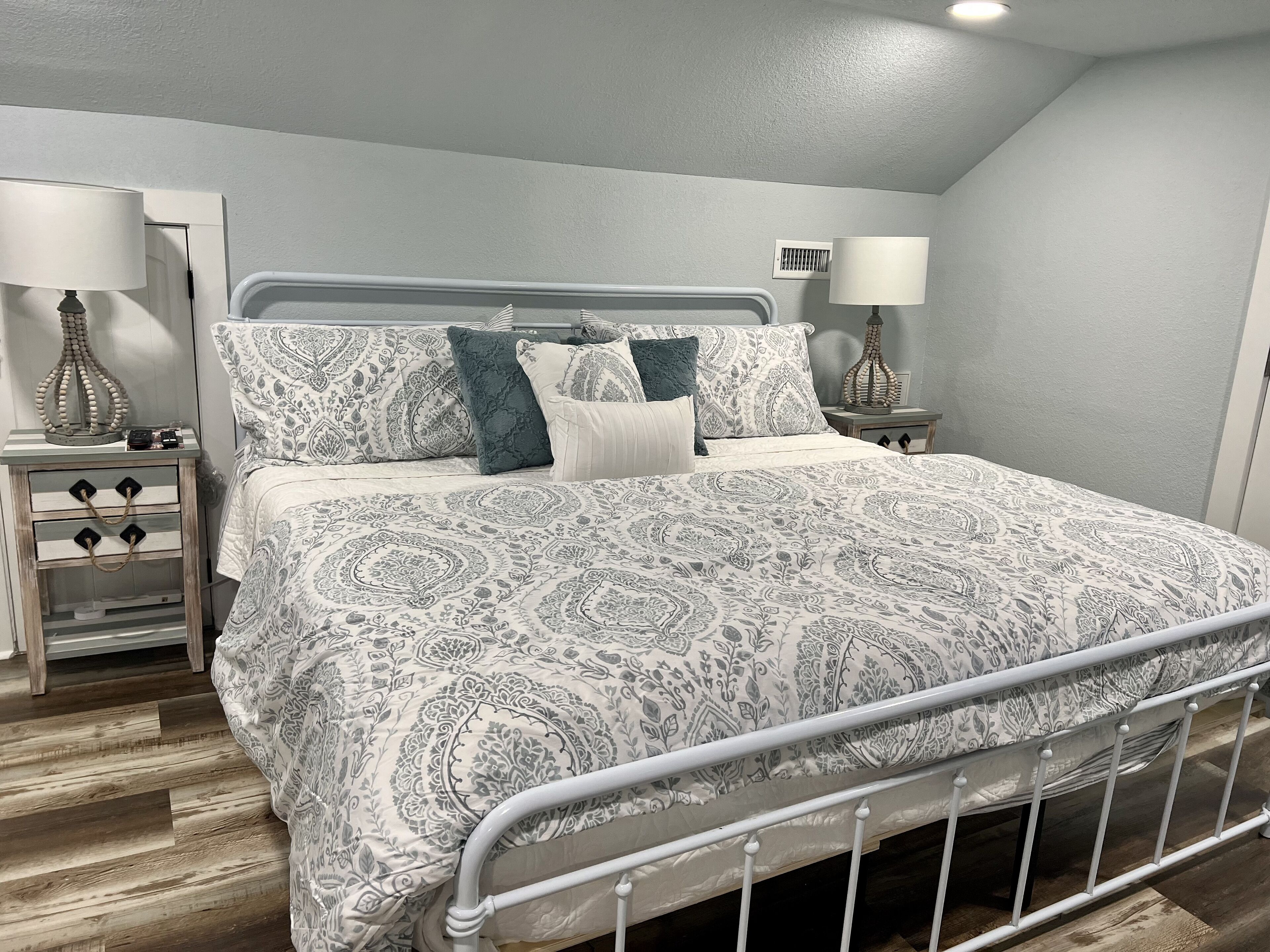 Un dormitorio con una cama, dos mesitas de noche y un aparador.