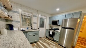 A modern kitchen with granite countertops, stainless steel appliances, and light blue cabinets. - Riverside Relaxer Cottage w/Hot Tub+LRG deck+fireplace, w/ Little TN River View (Franklin)