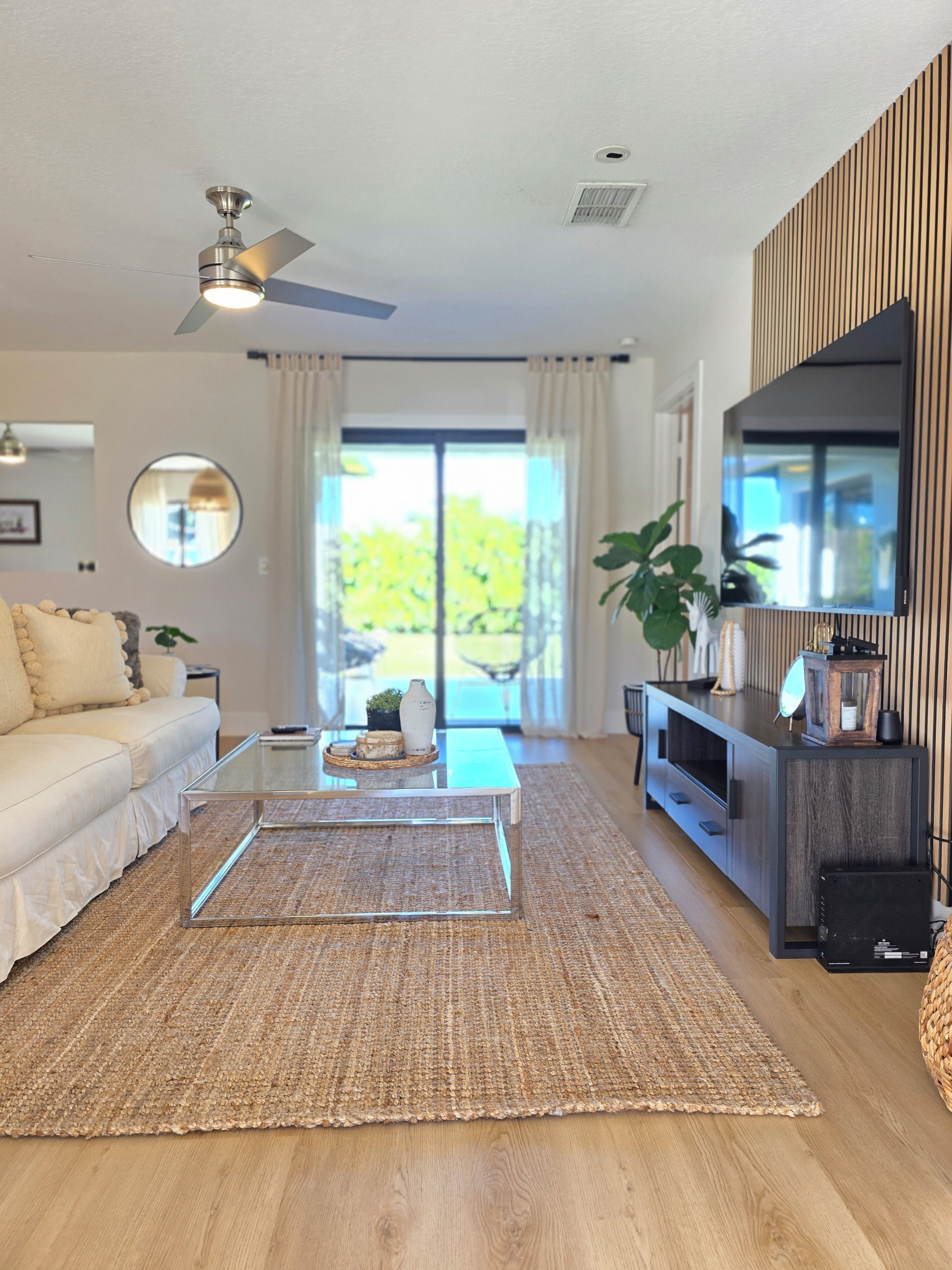 A modern living room with a sofa, coffee table, TV, and a ceiling fan.