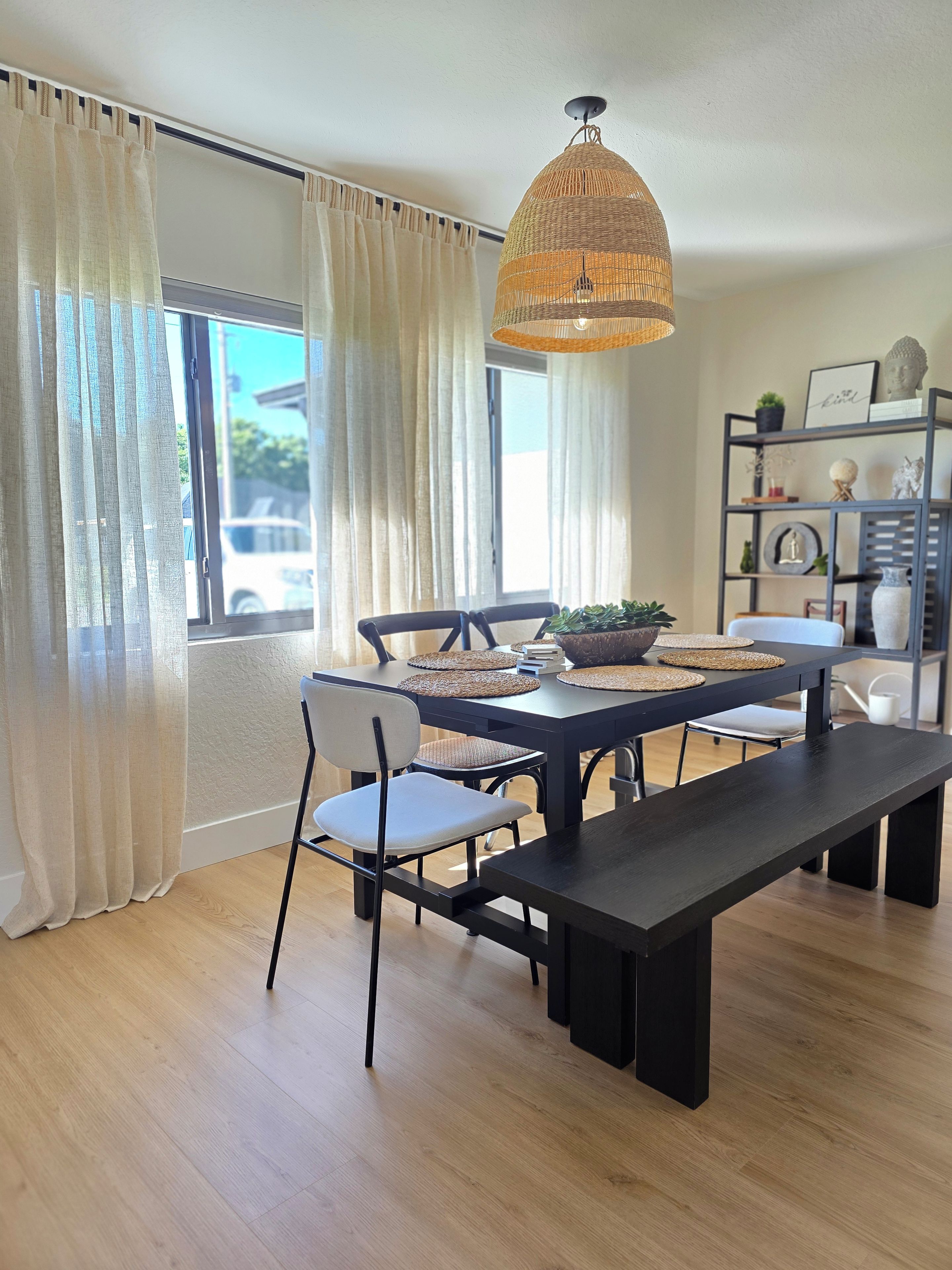 A dining area with a dark wooden table, chairs, and a woven pendant light.