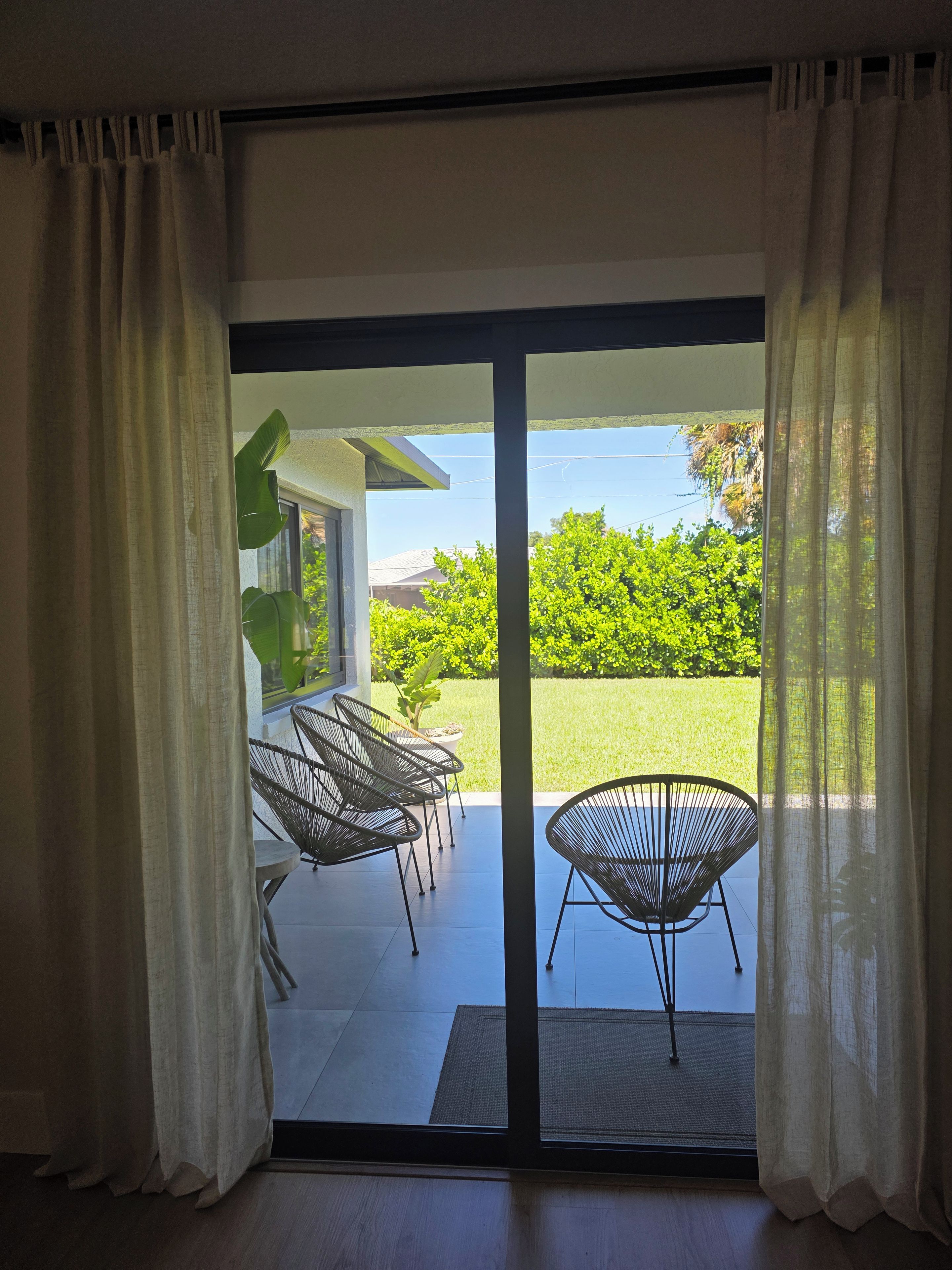 A room with a sliding glass door leading to an outdoor patio with chairs and a table.