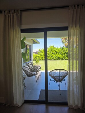 A room with a sliding glass door leading to an outdoor patio with chairs and a table. - Renovated Luxury Bohemian Home/Free parking (Naples)