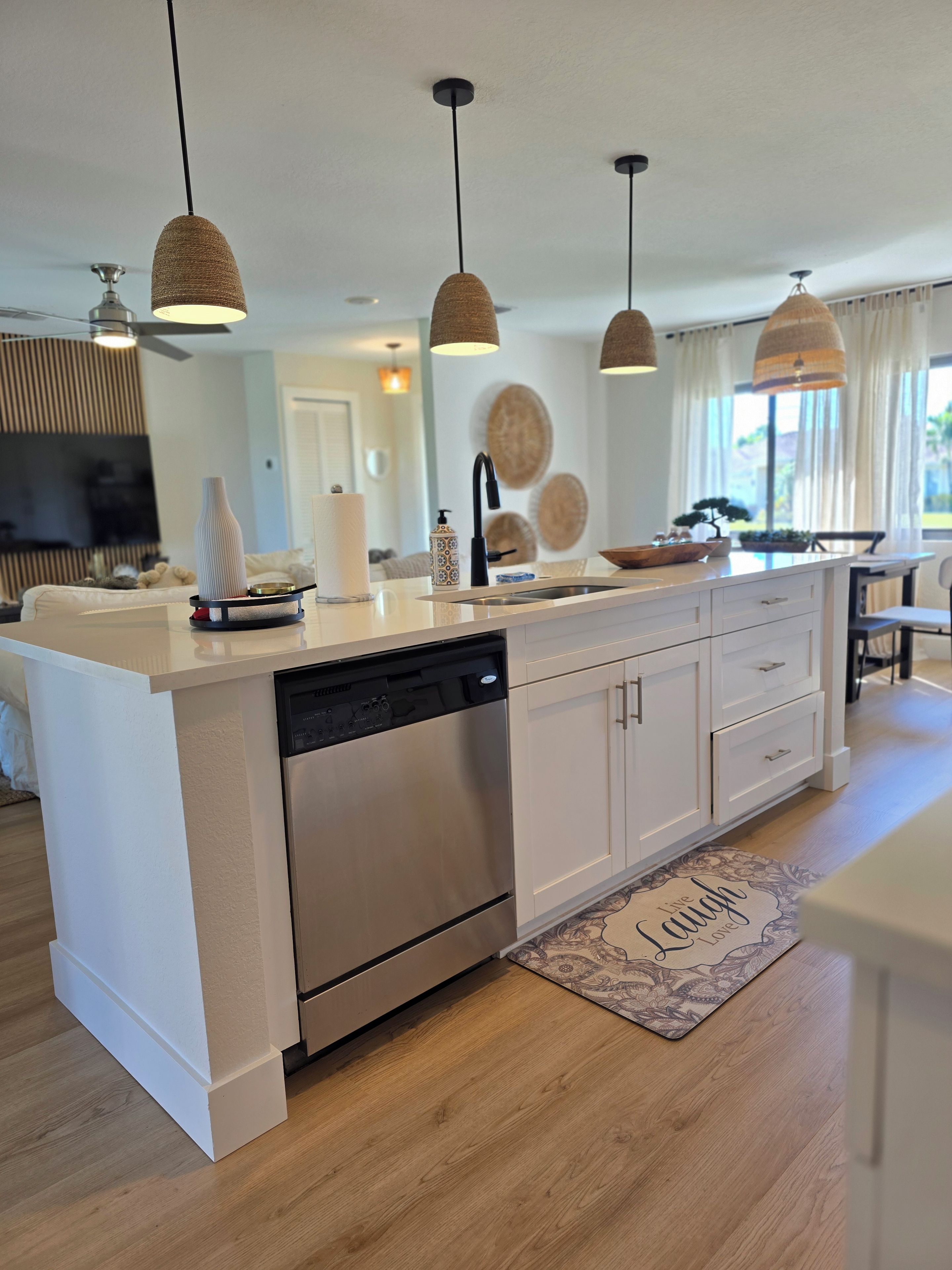 A modern kitchen with a dishwasher, a sink, and pendant lights.