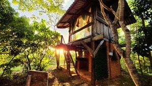 A treehouse with a wooden exterior, a staircase leading up to it, and a view of the surrounding greenery. - Ecopousada Toca do Guará (Alto Paraíso de Goiás)