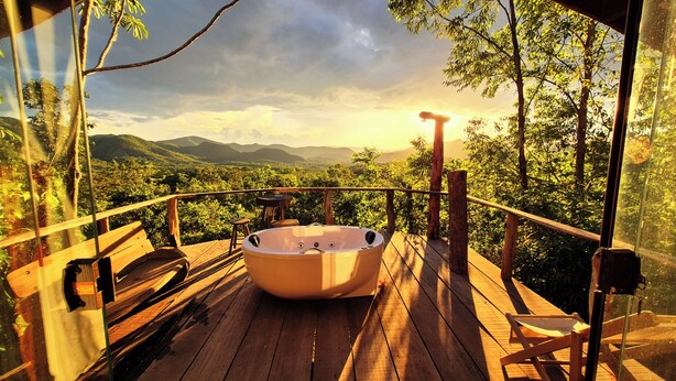 A wooden deck with a hot tub, wooden chairs, and a table. - Ecopousada Toca do Guará (Alto Paraíso de Goiás)
