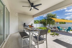 Une terrasse extérieure avec une table dressée pour les repas, des chaises et un ventilateur de plafond.