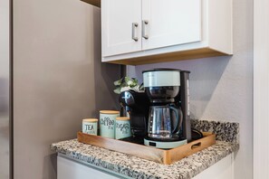 A kitchen counter with a coffee maker, a plant, and three containers labeled 'Tea Break,' 'Coffee Fix,' and 'Sugar Hit.'