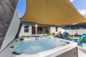 Ein Whirlpool mit Baldachin, Sitzgelegenheiten im Freien und eine Grillanlage.