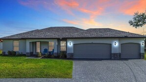 Une maison à deux étages avec un garage, une véranda et une pelouse bien entretenue.