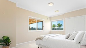 A bedroom with a bed, two windows, a ceiling light, and a plant. - Beautiful Large Country Home in the Perfect Location with tennis court & theatre (Worrigee)