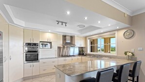 A modern kitchen with built-in appliances, a large island, and a view of the outdoors. - Beautiful Large Country Home in the Perfect Location with tennis court & theatre (Worrigee)