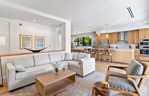 Une cuisine moderne avec des meubles en bois, des appareils en acier inoxydable et un coin repas doté d’un bar.