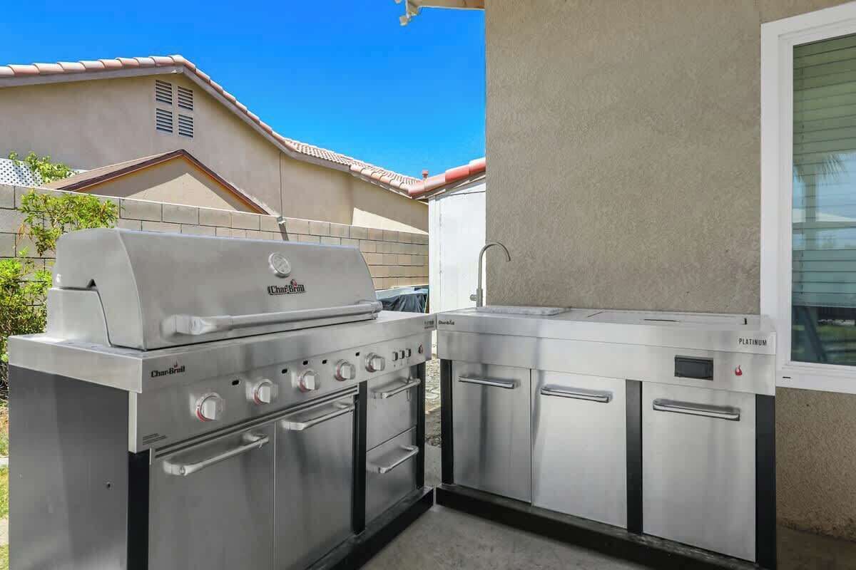 A patio with a Char-Broil grill, a stainless steel oven, and a built-in refrigerator.