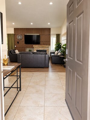 Een moderne woonkamer met een bank, een flatscreen televisie en een wand van houten panelen.