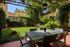 A patio with a table and chairs, surrounded by greenery and a view of buildings. - Apartments Florence - Architech House with swimming pool (Firenze)