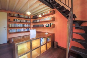 A library with bookshelves, a wooden desk, and a spiral staircase. - Apartments Florence - Architech House with swimming pool (Firenze)