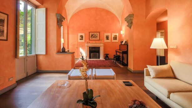 Un intérieur comprenant une cheminée, un coin salon et une vue dégagée sur l’extérieur, accessible par une arche.