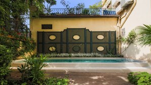 Un espace piscine doté d’une terrasse en bois, entouré de verdure et agrémenté d’un mur décoratif orné d’ouvertures circulaires.
