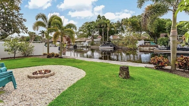 A landscaped outdoor area with a fire pit, a pond, and a boat dock. - Lakehouse Living w/ Firepit and Boat Dock to relax and Enjoy the Sunset (palm harbor)