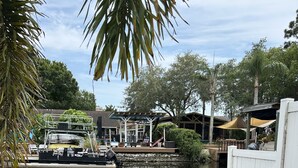 A serene outdoor area with a water body, surrounded by lush greenery and a covered seating area. - Lakehouse Living w/ Firepit and Boat Dock to relax and Enjoy the Sunset (palm harbor)