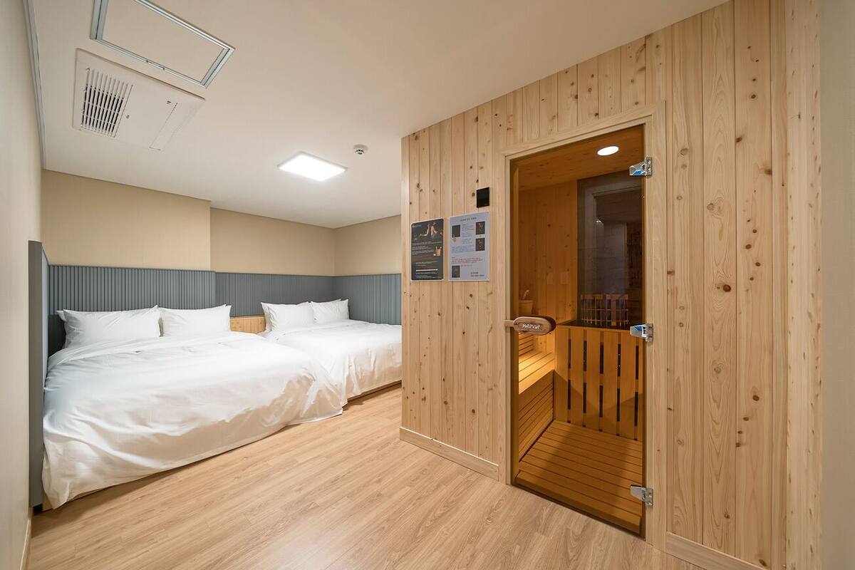 A hotel room with two beds, wooden paneling, a wooden door, and a small wooden staircase.